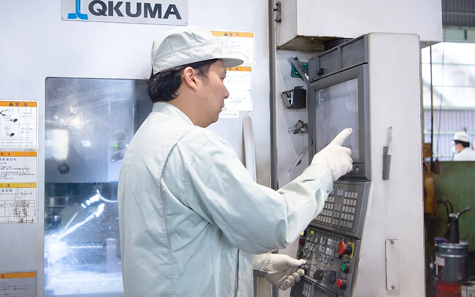 機械オペレーターの男性が機械の操作盤を操作している様子