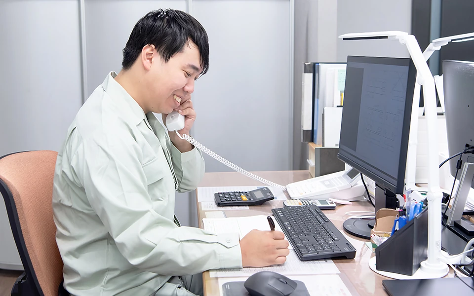 デスクで電話応対している営業職の男性